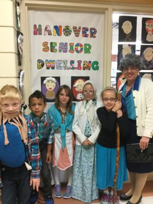 children in front of sign that displays Hanover Senior Dwelling
